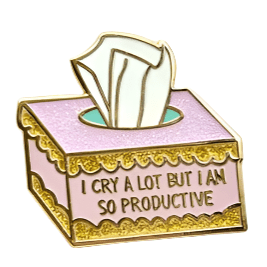 The My Cutesy Era pink and gold enamel pin features a tissue box with I CRY A LOT BUT I AM SO PRODUCTIVE on the front and tissues poking out, making this pin both fun and relatable.