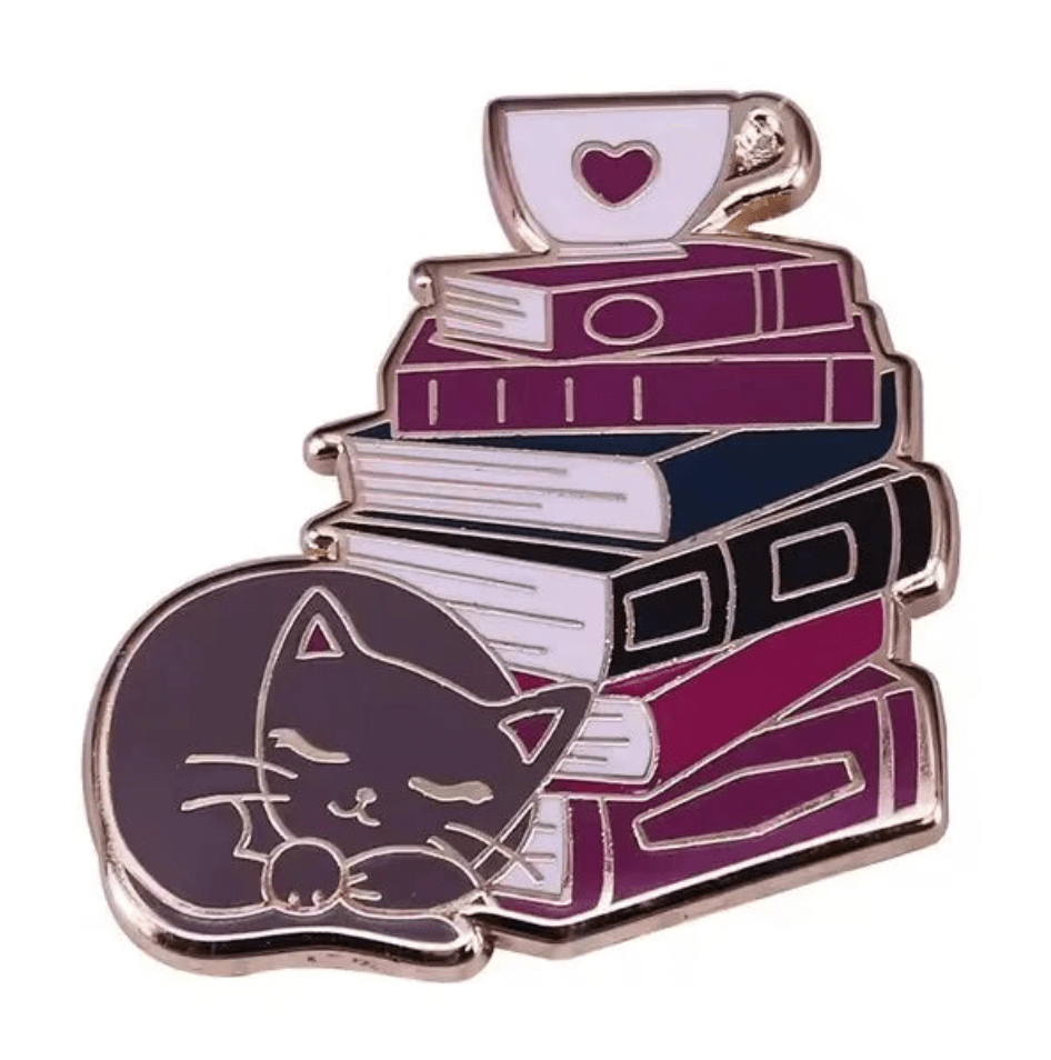 Library pin features a sleeping cat curled up by vibrant books, topped with a white teacup and pink heart—perfect for collectors of book enamel pins and ideal as a gift for any book lover.