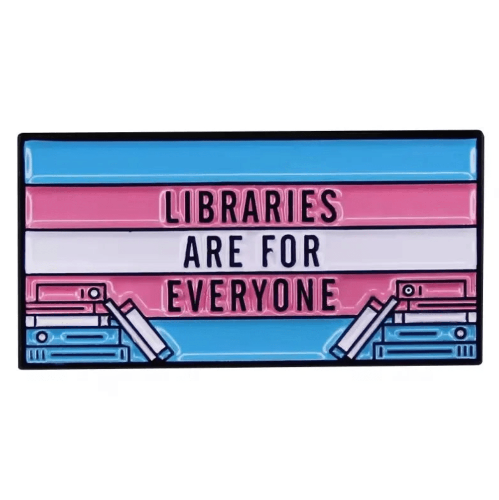 A rectangular trans flag badge features Libraries Are For Everyone on blue, pink, and white stripes with stylized books—perfect as a library pin or thoughtful gift for any book lover.
