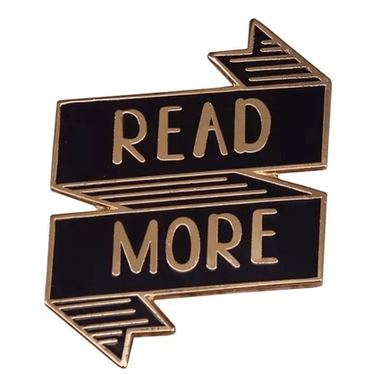 Black and gold ribbon-shaped enamel library pin features READ MORE in bold gold letters—perfect for book lovers, collectors, or as a unique literary-themed gift.