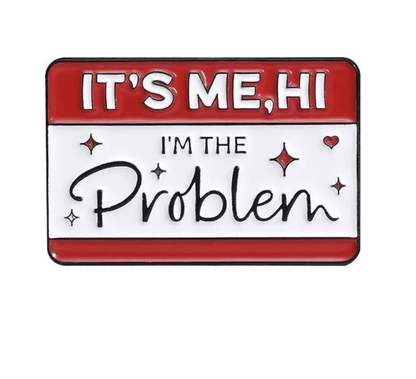 A rectangular enamel pin with a red and white background features the text ITS ME, HI IM THE Problem accented by small hearts and sparkles around Problem.