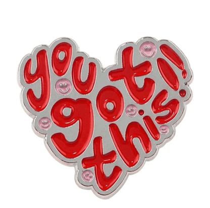 My Cutesy Era’s love heart enamel pin features bold red “You got this!” text with small pink smiley faces, making it the perfect motivational accessory to brighten your day.