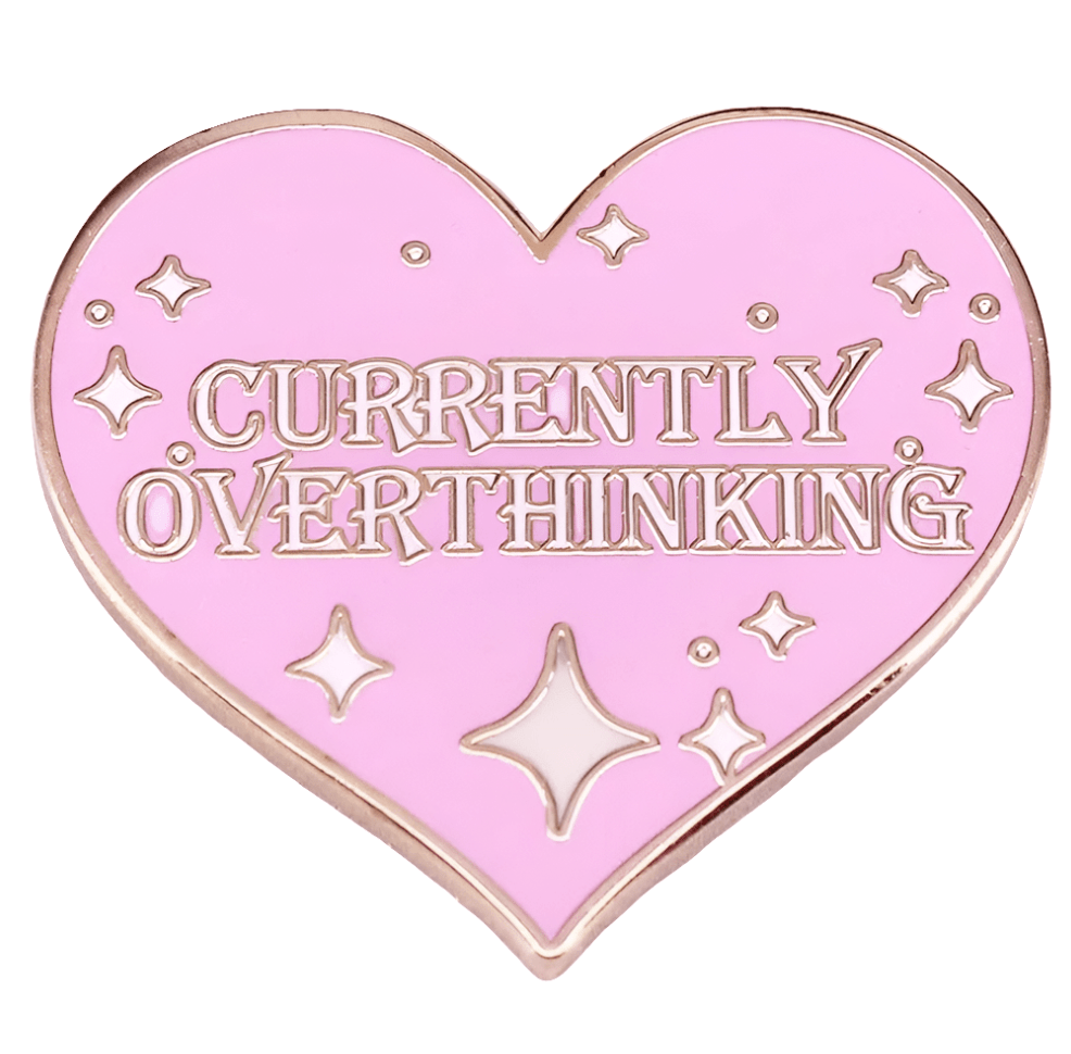 The My Cutesy Era pink, heart-shaped feminist enamel pin with gold trim displays “CURRENTLY OVERTHINKING” and is adorned with small star and sparkle designs.