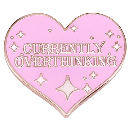 The My Cutesy Era pink, heart-shaped feminist enamel pin with gold trim displays “CURRENTLY OVERTHINKING” and is adorned with small star and sparkle designs.