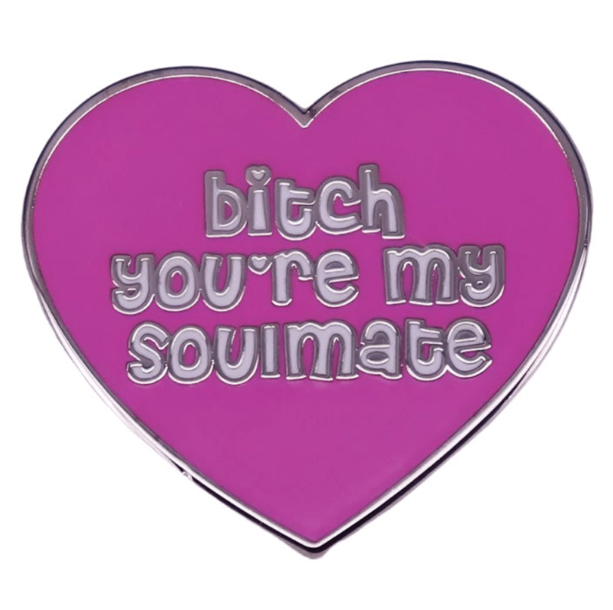 The My Cutesy Era pink heart enamel pin features silver edges and the phrase “bitch you’re my soulmate” in fun silver lettering.