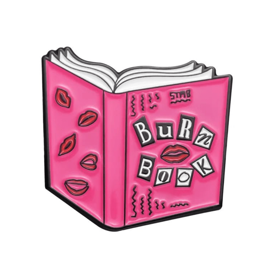 Illustration of an open pink Burn Book with cut-out letters and red lips, inspired by Mean Girls—ideal for enamel pin fans or collectors. Designed by My Cutesy Era.