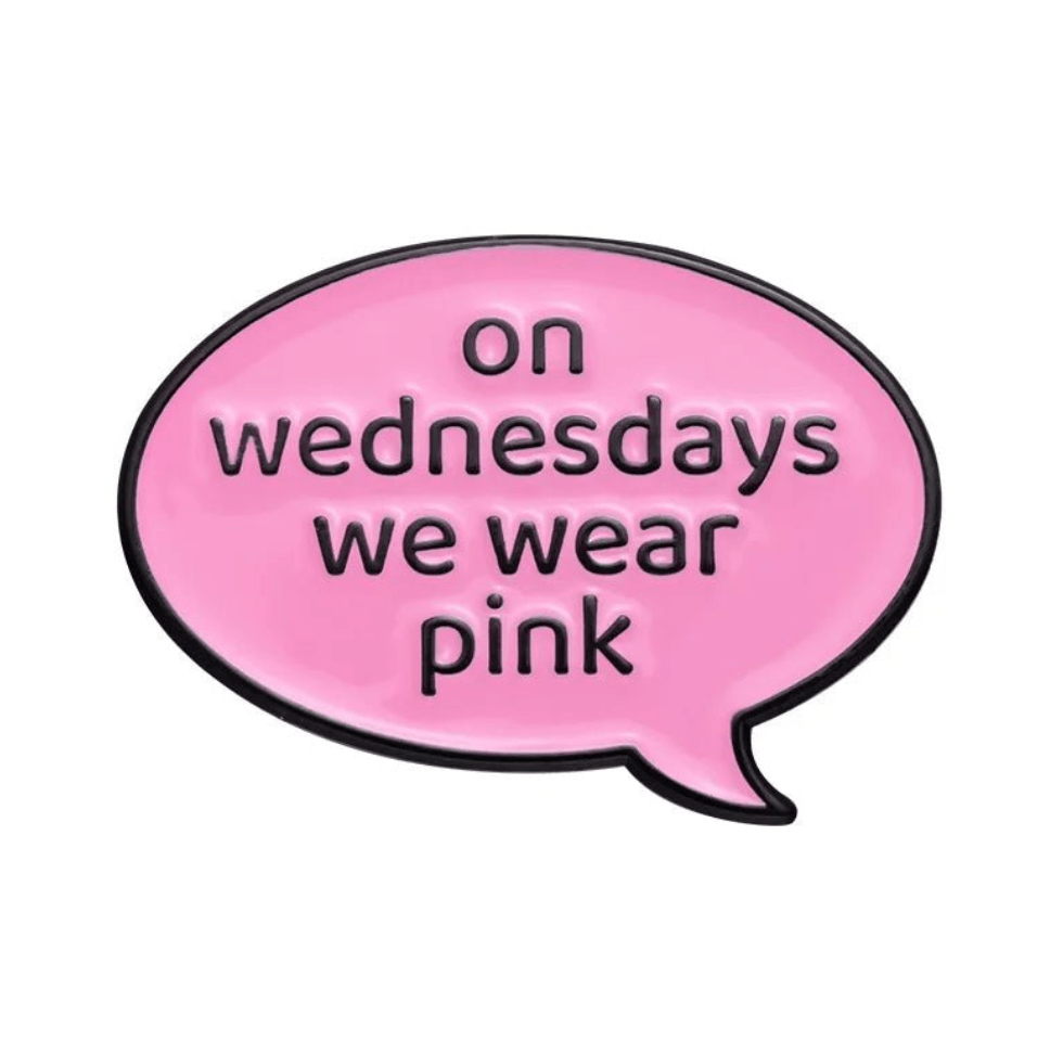 A pink speech bubble enamel pin by My Cutesy Era, featuring on wednesdays we wear pink in lowercase black letters—perfect for Mean Girls fans.