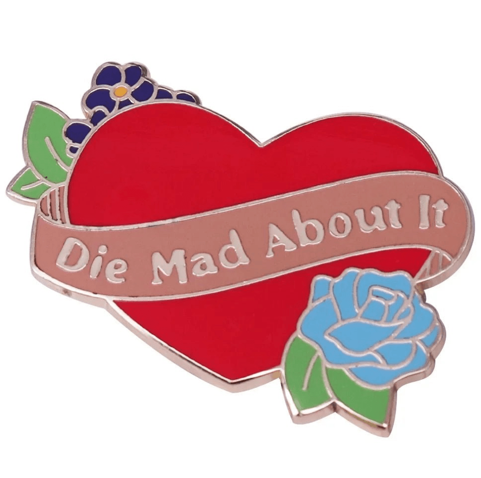 My Cutesy Era’s vibrant floral enamel pin features a red heart with purple and blue flowers and a pink banner that says Die Mad About It in white letters.