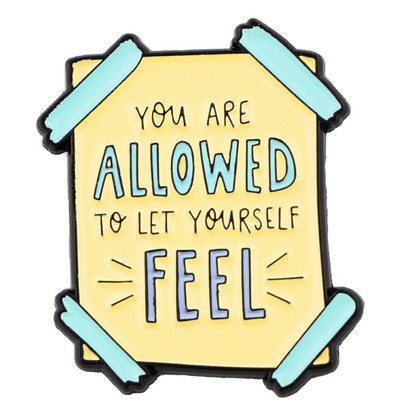 A yellow sign from My Cutesy Era with teal tape on the corners reads You are allowed to let yourself feel, featuring allowed and feel in larger blue letters—a motivational reminder supporting mental health.