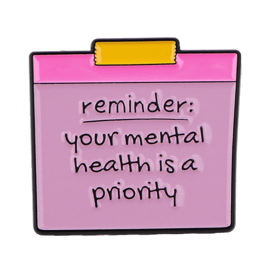 The My Cutesy Era enamel pin—a pink and purple clipboard—features the message reminder: your mental health is a priority, offering daily motivation and positive affirmation you can wear.