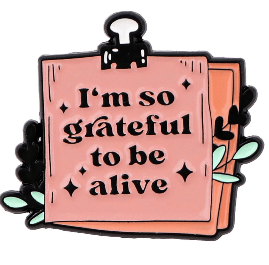 The My Cutesy Era notepad is pink with “I’m so grateful to be alive” written on it, decorated with leaves and a black binder clip—a motivational affirmation for mental health.