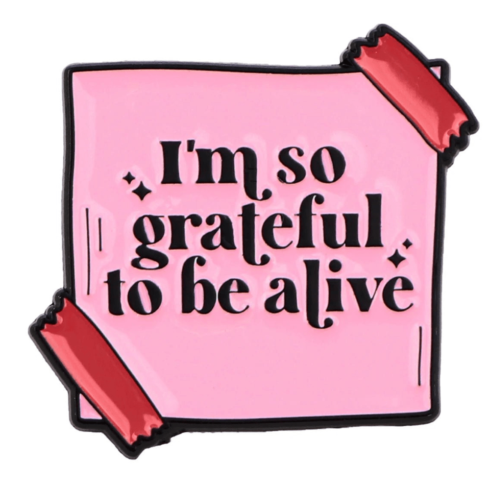 A pink note from My Cutesy Era with red tape on two corners reads, I’m so grateful to be alive in bold black—a motivational reminder to share positivity and support mental health.