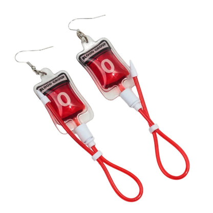 Kiss Me Laters gothic blood bag earrings are shaped like BLOOD GROUP O bags, filled with red liquid and red tubing loops—a unique nurse accessory or edgy statement piece.