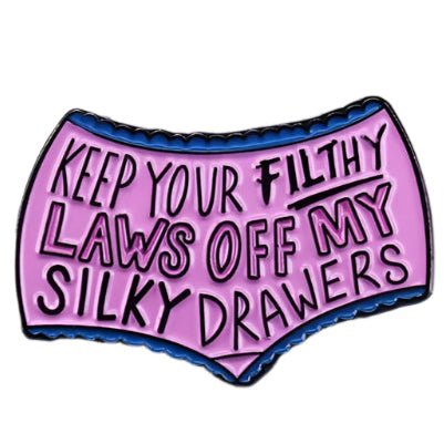 Enamel pin in pink and purple—shaped like underwear—features the bold message “KEEP YOUR FILTHY LAWS OFF MY SILKY DRAWERS.” A fierce feminist accessory for those who believe well-behaved women rarely make history.