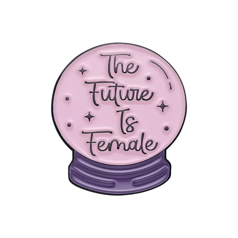 Pink crystal ball with small stars and The Future Is Female text sits on a purple base like a bold feminist pin, shown against a white background.