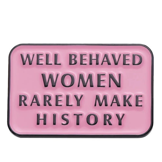 A rectangular pink enamel pin with raised black letters reading WELL BEHAVED WOMEN RARELY MAKE HISTORY—a bold accessory for self-love and empowerment.
