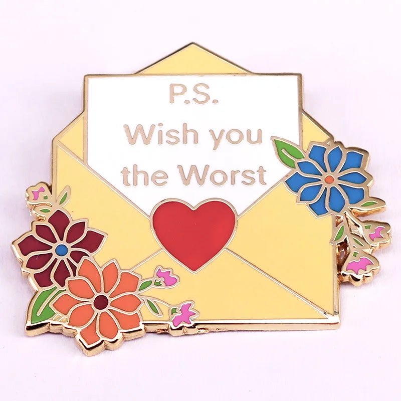 Yellow floral enamel pin is shaped like an open envelope with colorful flowers, a red heart, and a white card that reads “P.S. Wish you the Worst.”.