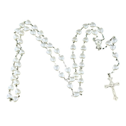 A My Cutesy Era rosary necklace with white heart-shaped beads linked together and a silver crucifix at the end, displayed in a loose, wavy pattern on a white background.