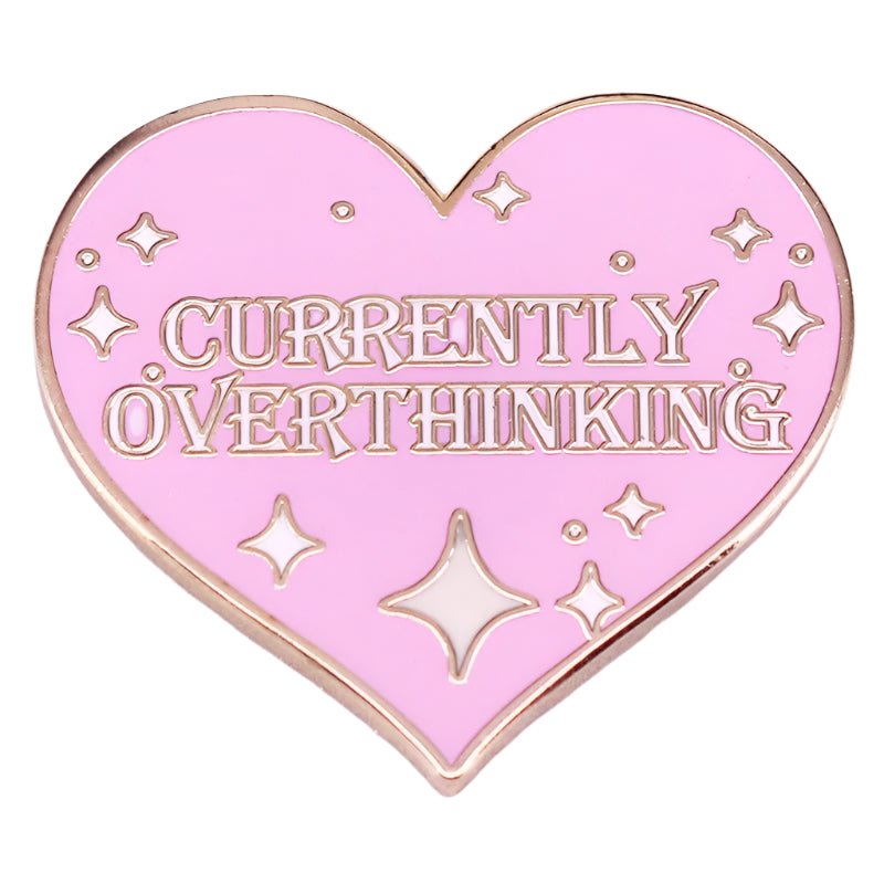 The My Cutesy Era enamel pin is heart-shaped and pink with gold trim and sparkles, featuring CURRENTLY OVERTHINKING in bold gold letters.
