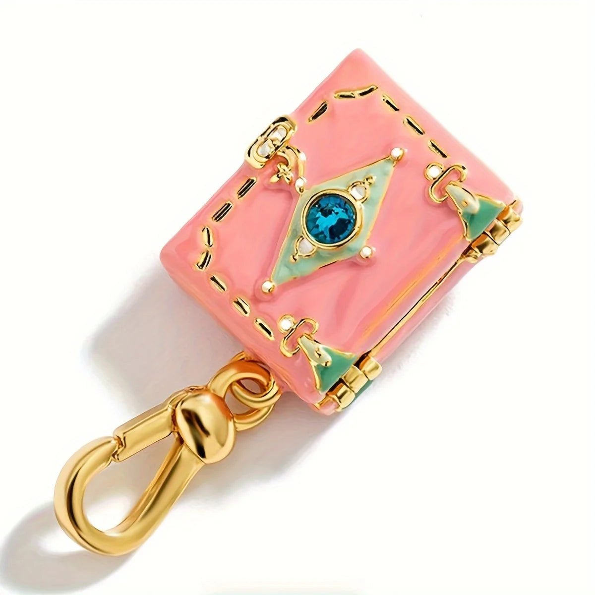 A pink, suitcase-shaped gold enamel pendant by features green accents, a blue center gem, and a gold clasp for attaching to a bracelet or necklace, photographed on a white background.