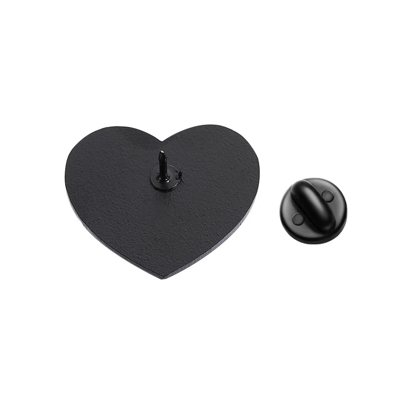 Black enamel heart-shaped pin with a pointed back is displayed beside its round black backing on a white background.