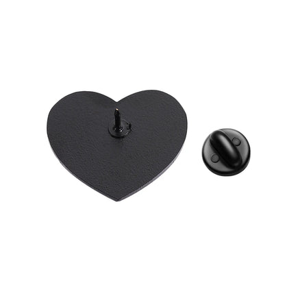 Black enamel heart-shaped pin with a pointed back is displayed beside its round black backing on a white background.