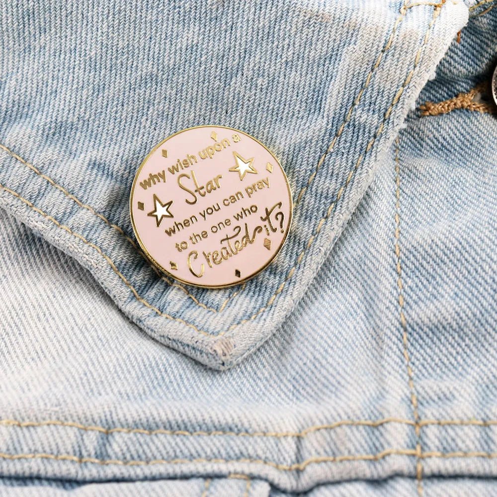 Pink and gold enamel badge (3cm x 3cm) sits on a light blue denim jacket pocket. It reads, Why wish upon a star when you can pray to the one who created it? with gold stars and accents.
