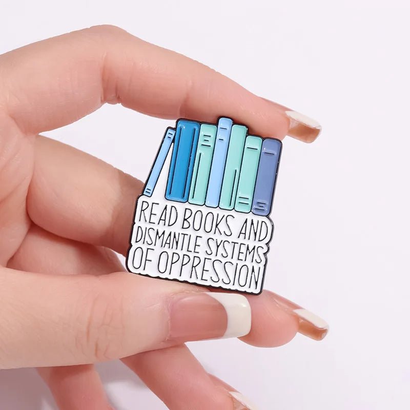 A hand holds a My Cutesy Era book pin showing colorful books above the text "Read books and dismantle systems of oppression"—a perfect accessory and thoughtful gift for any book lover.