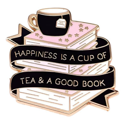 The My Cutesy Era enamel pin features a teacup on pink books with gold stars and a black ribbon that reads, Happiness is a cup of tea & a good book—a perfect gift for tea and book lovers.