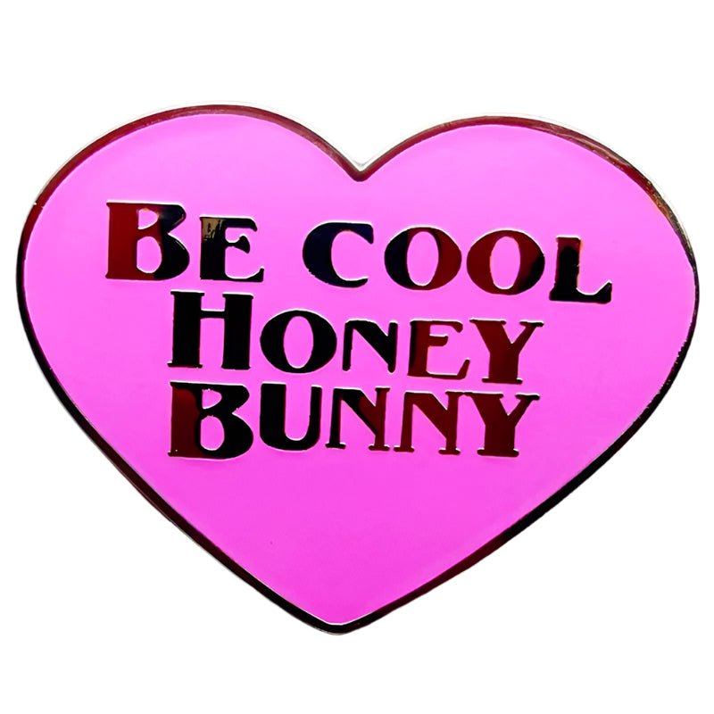 The My Cutesy Era pink heart-shaped enamel pin displays “Be Cool Honey Bunny” in bold black and red letters.