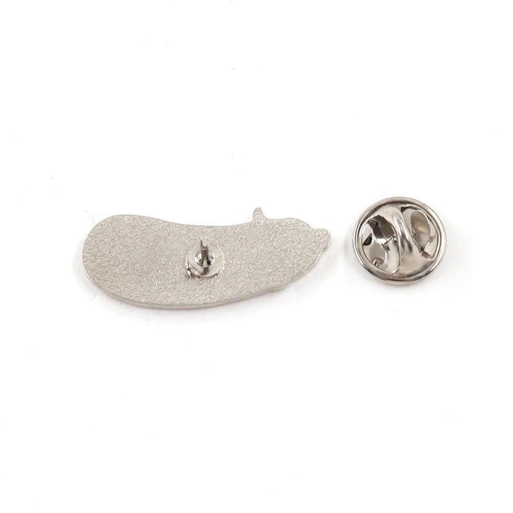 A silver-colored, cute enamel pickle pin lies next to its round butterfly clasp on a white background.