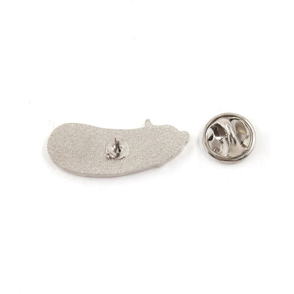 A silver-colored, cute enamel pickle pin lies next to its round butterfly clasp on a white background.