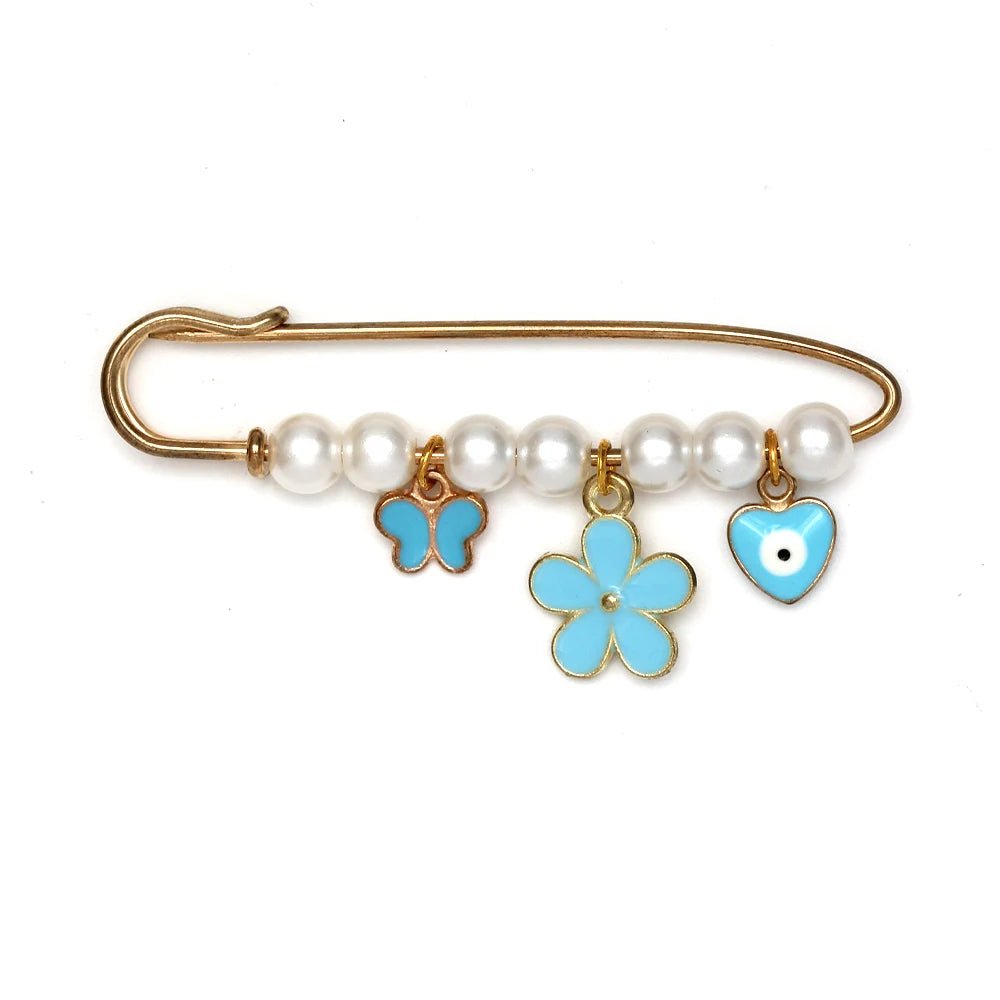 Kiss Me Laters gold safety pin features white beads and three blue charms—a butterfly, a flower, and an evil eye heart—making it a unique beads and charms brooch or thoughtful baby shower gift.