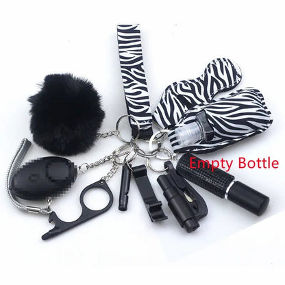 The Kiss Me Later zebra-print keychain set features personal safety accessories—an empty bottle spray, whistle, black pom-pom, bottle opener tool, and more—ideal for outdoor adventures or everyday use.