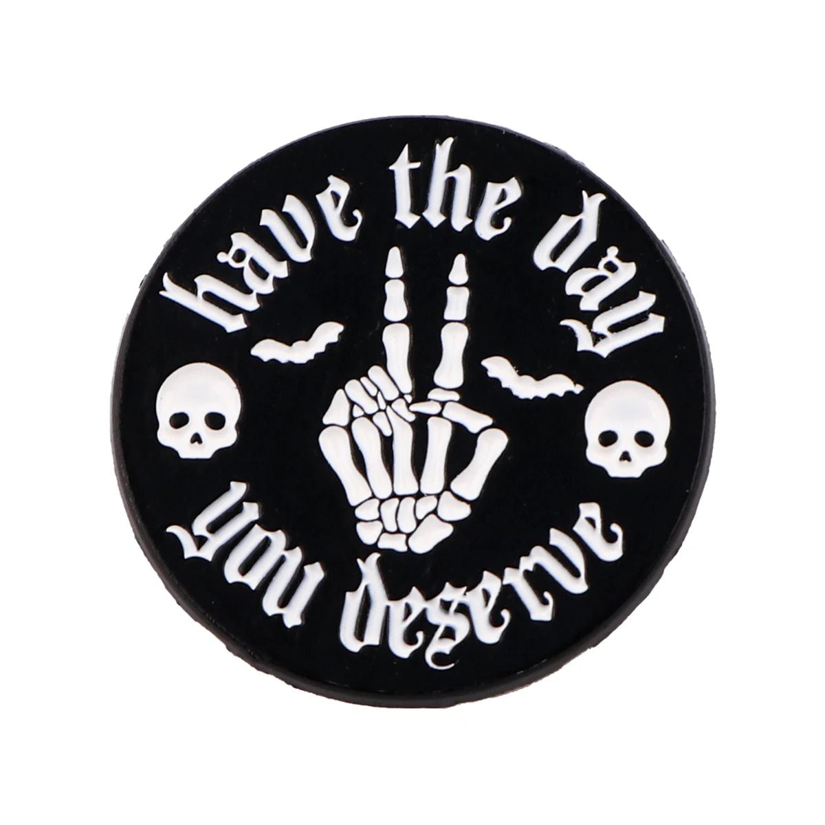The Kiss Me Later round black enamel pin features a skeleton hand making a rude gesture, have the day you deserve in white text, plus spooky details like two skulls and two bats.