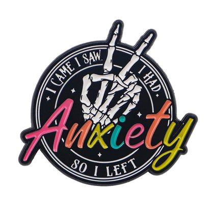 The Kiss Me Later skeleton hand enamel pin flashes a peace sign, with I came, I saw, I had anxiety, so I left around it. Anxiety stands out in colorful cursive—a playful accessory for anyone into quirky style!.