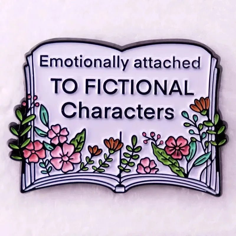 An enamel pin of an open book with flowers and the text “Emotionally attached TO FICTIONAL Characters”—perfect for romance readers or any book lover’s collection.