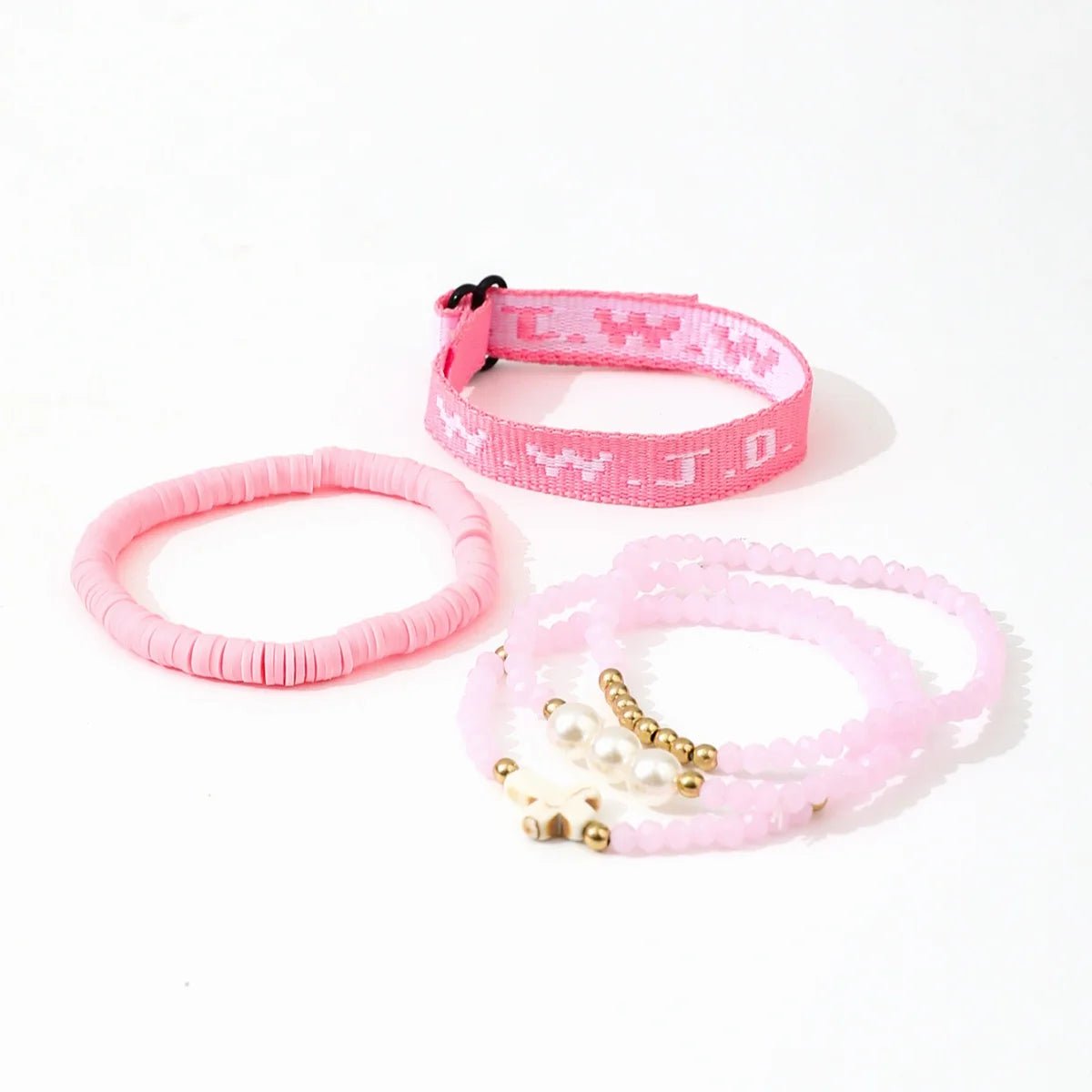 The Kiss Me Later pink bracelet stack includes a woven WWJD bracelet, a solid pink disc bracelet, and two beaded bracelets with gold and white beads, all displayed on a white background.