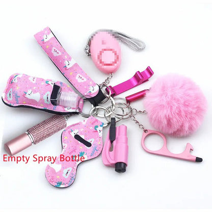 The Kiss Me Later keychain set features pink and purple personal safety accessories—empty spray bottle, alarm, whistle, fluffy pom-pom, touch tool, lip balm, and sanitizer holder—ideal for outdoor adventures. Text reads Empty Spray Bottle.