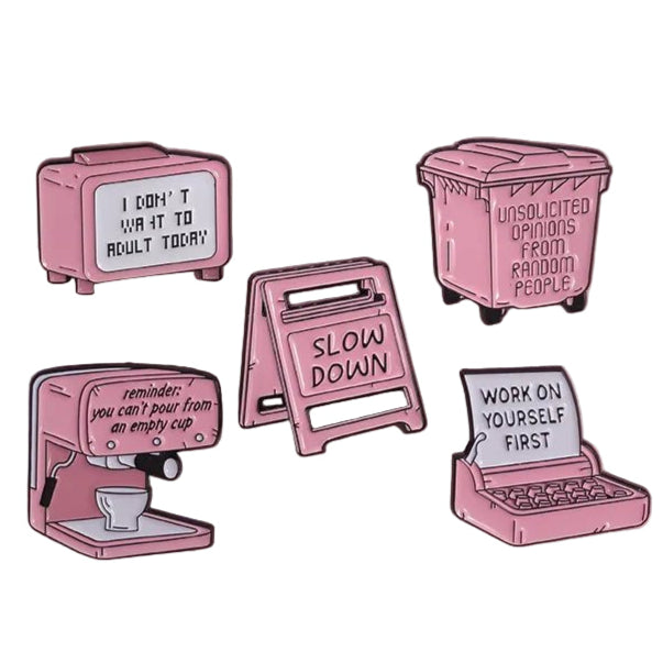Five pink enamel pins on a pink background, with messages like “Slow down” and “Work on yourself first”—the perfect pick-me-up when you need motivation that even espresso or caution signs cant provide.