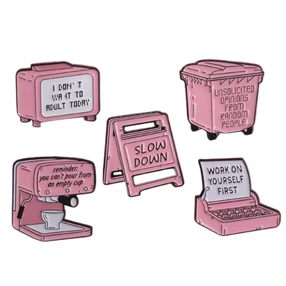 Five pink enamel pins on a pink background, with messages like “Slow down” and “Work on yourself first”—the perfect pick-me-up when you need motivation that even espresso or caution signs cant provide.