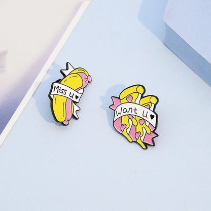 Two enamel pins rest on a light blue surface: one is a peeled banana with “Miss u,” the other shows a bunch of bananas and “Want u.” Cute pink and yellow designs—perfect for Miss You pin collectors!.