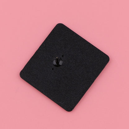 A black, square Kiss Me Later clock movement mechanism with a central spindle sits on a pink background, surrounded by subtle spooky vibes.