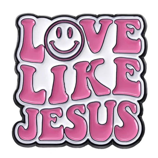 Text in bold, retro pink letters reads “Love Like Jesus,” with the “O” as a smiley face. This playful pin pops on white—perfect to wear or gift as a cheerful pink enamel Jesus accessory.