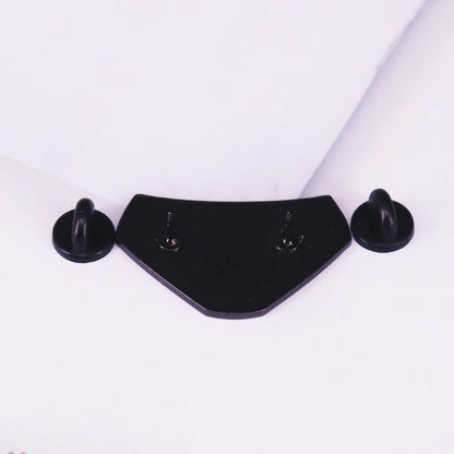 A black, angular metal plate features two side hooks and two central screws—ideal for displaying enamel pins or as unique decor for your Book Club meetings.