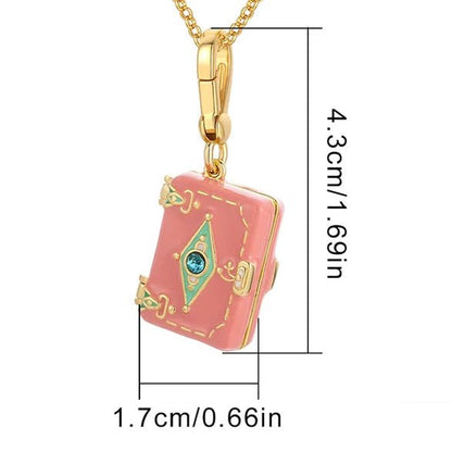 My Cutesy Era gold necklace with a pink enamel book pendant, blue gem, and gold accents. The love letter pendant is 4.3 cm tall by 1.7 cm wide, crafted with elegant detail for a charming look.