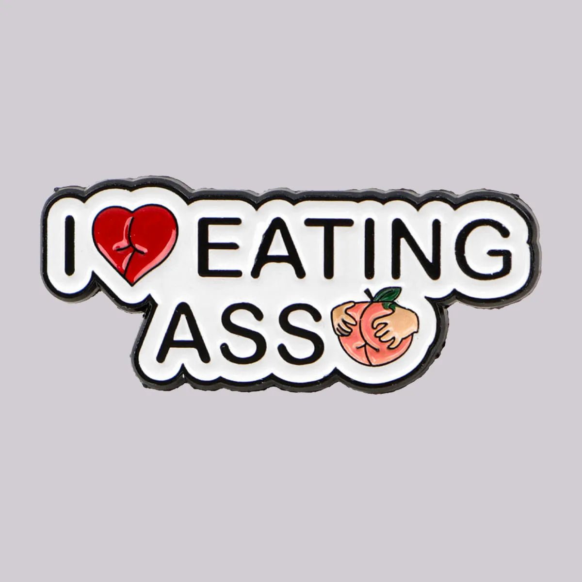 The Kiss Me Later peach pin features “I Love Eating Ass” with a heart for “love” and ASS as a peach emoji held by hands. Measures 3.5cm x 1.5cm on a light gray background.