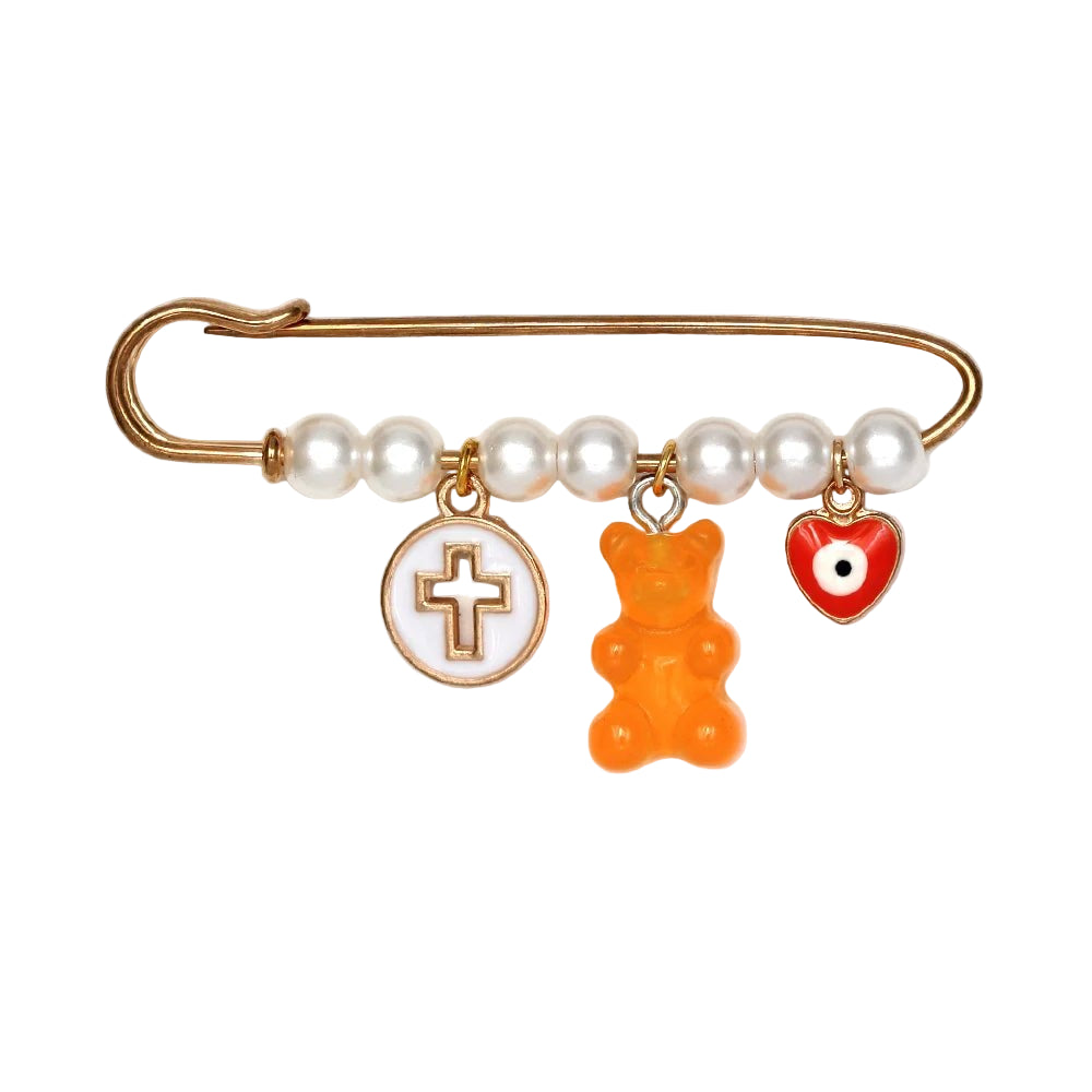 The Kiss Me Later gold safety pin brooch features five pearl beads and three charms—a round cross, orange gummy bear, and red heart with an evil eye—making it a stylish and unique baby shower gift.
