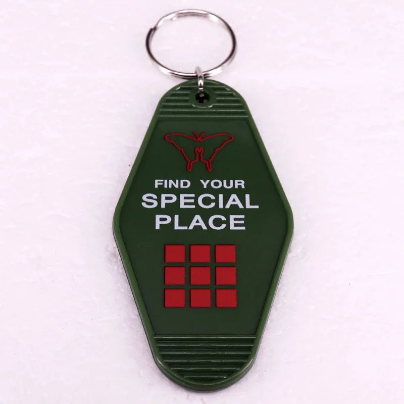 A green retro hotel key ring from Kiss Me Later with a metal ring, red butterfly icon, FIND YOUR SPECIAL PLACE in white text, and three rows of three red squares—paying homage to colorful pop culture key rings.