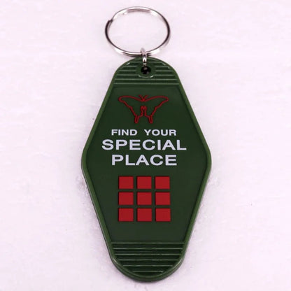 A green retro hotel key ring from Kiss Me Later with a metal ring, red butterfly icon, FIND YOUR SPECIAL PLACE in white text, and three rows of three red squares—paying homage to colorful pop culture key rings.
